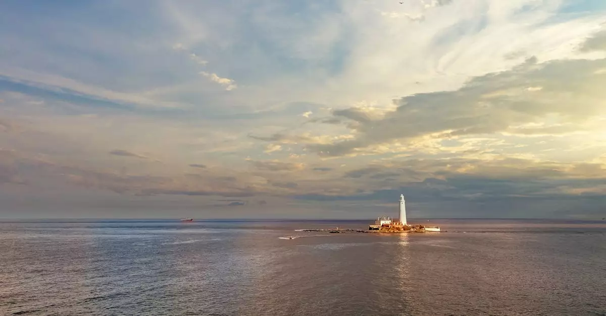 Breathtaking view of St Mary's Lighthouse surrounded by vast ocean under a dramatic sky at sunset.