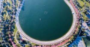 Stunning aerial shot of a circular lake within a lush Dubai park with pathways and greenery.