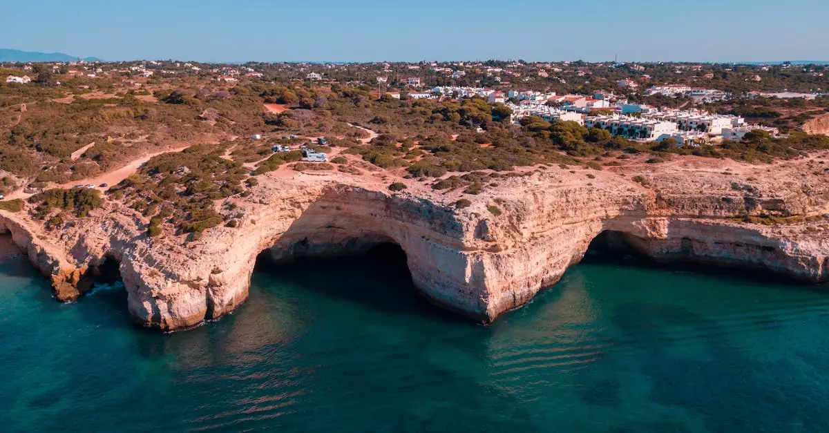 Stunning aerial view of Benagil Cave and coastal cliffs in Algarve, Portugal, with clear turquoise waters.