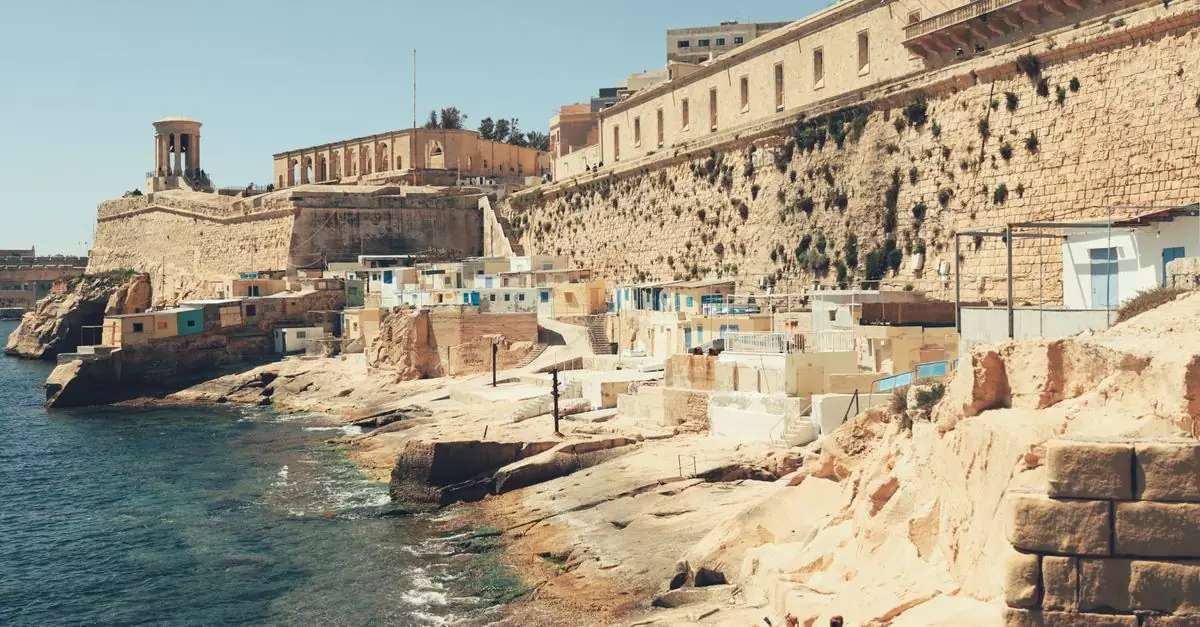 Scenic view of Valletta's historic waterfront with limestone architecture and turquoise sea.