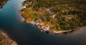 Explore the serene beauty of a Swedish island village from above with lush forests and calm coastal waters.