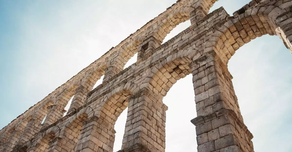 Low angle view of the historical Segovia Aqueduct's stone arches under a clear sky.