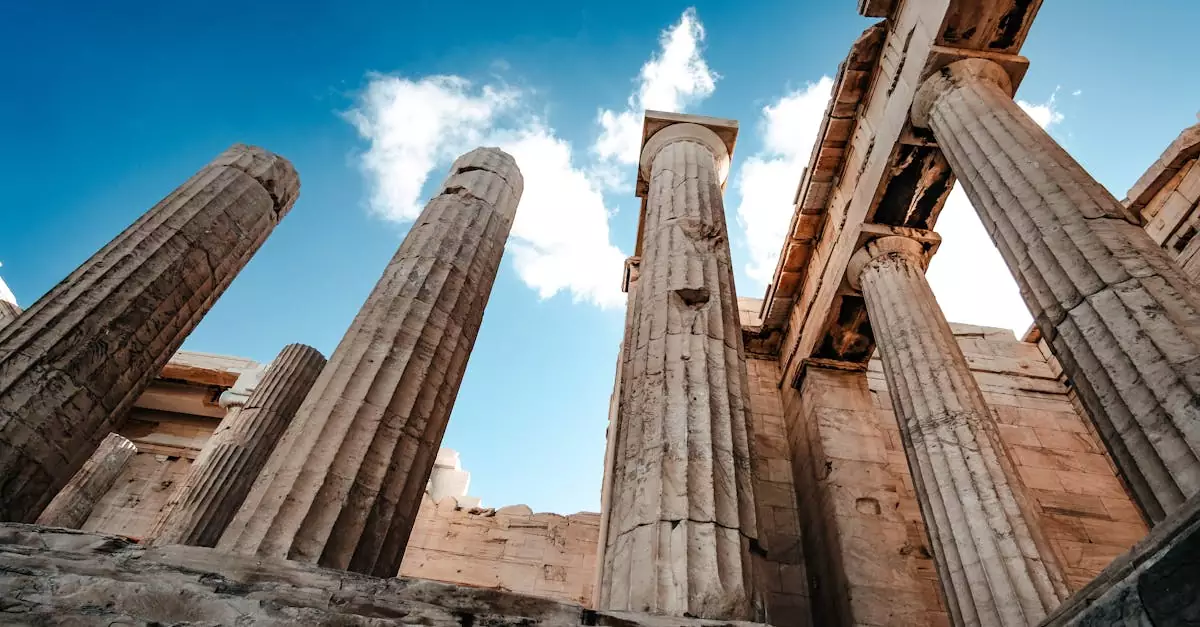 A low-angle view of the ancient columns at the Acropolis in Athens, Greece, against a bright sky.