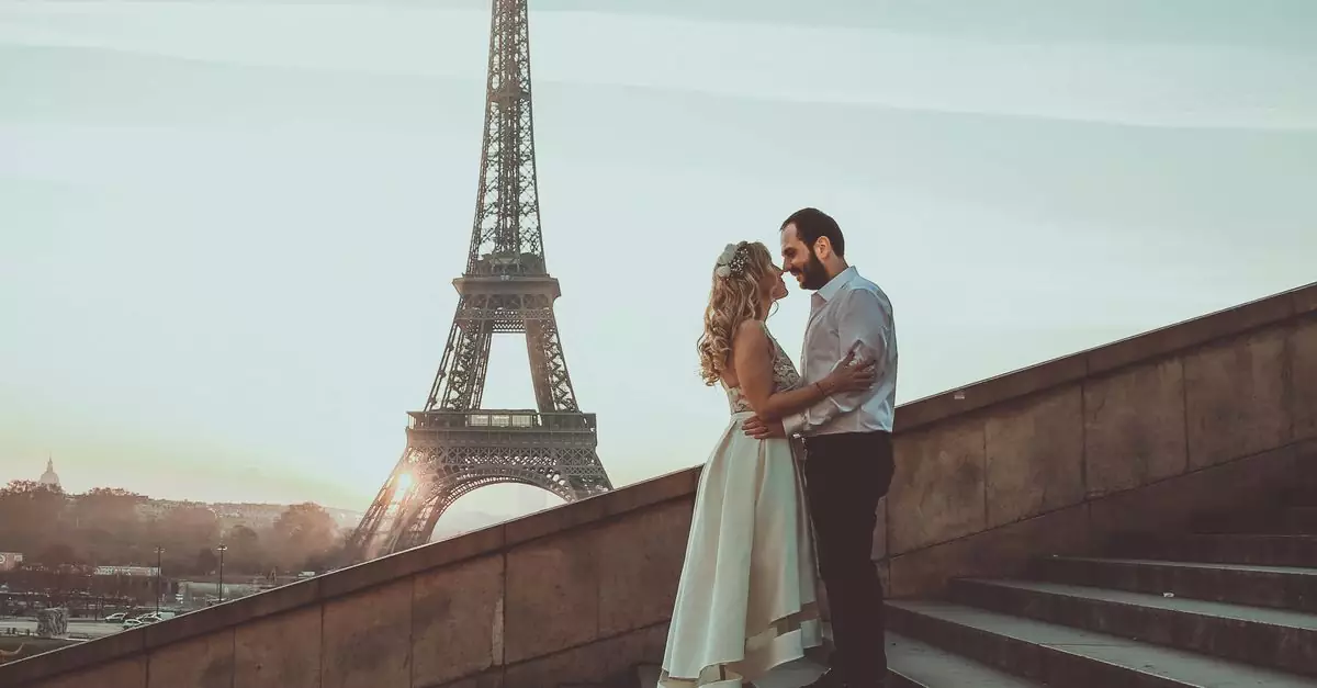 A romantic embrace of a couple at sunset with the Eiffel Tower in the background.