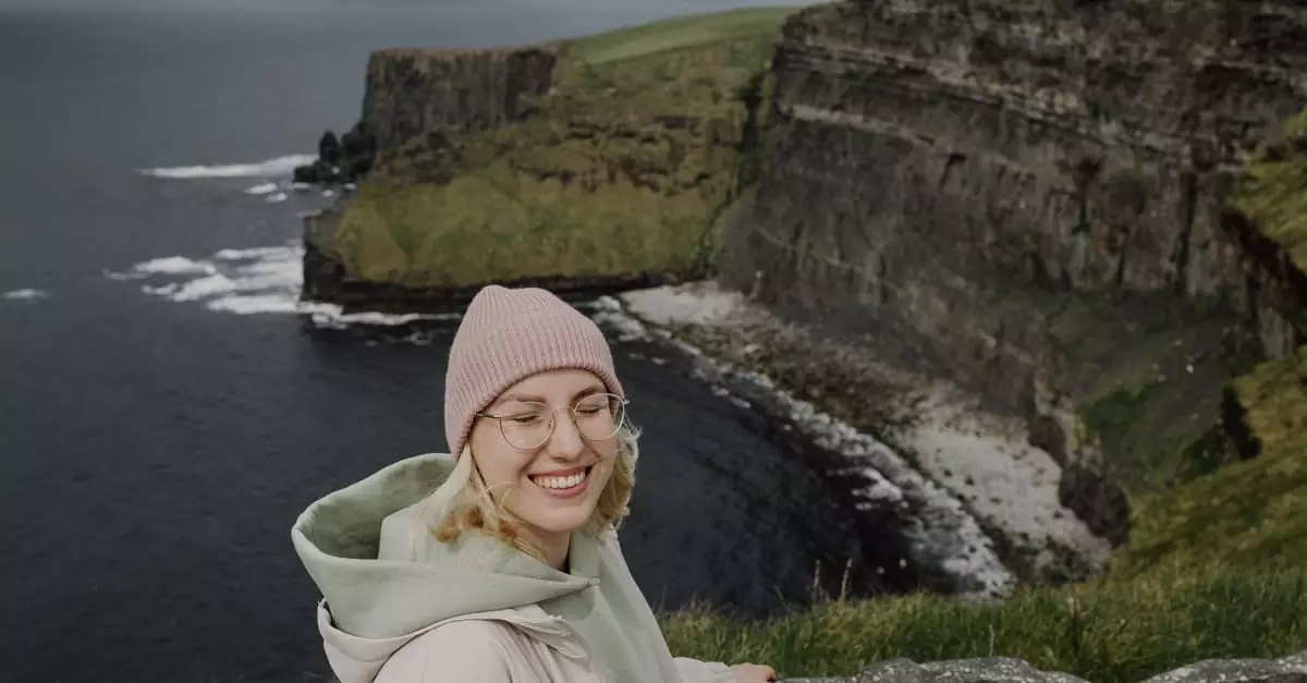 Happy woman enjoying a scenic view of the Cliffs of Moher in Ireland.
