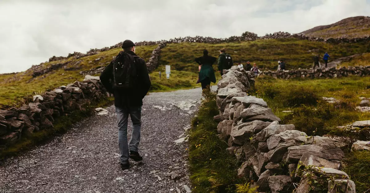 Travelers walking along a historic stone path on Inishmore, Ireland, surrounded by lush greenery.