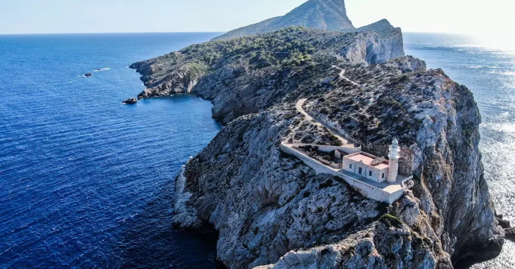Stunning aerial photo of Punta Grossa Lighthouse on a rocky cliff surrounded by the deep blue ocean.