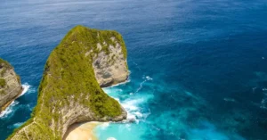 Stunning aerial view of Kelingking Beach's turquoise waters and unique rock formations in Bali, Indonesia.