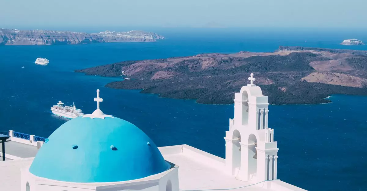 A stunning view of the iconic blue dome and church in Santorini with the Aegean Sea and cruise ships in the background.