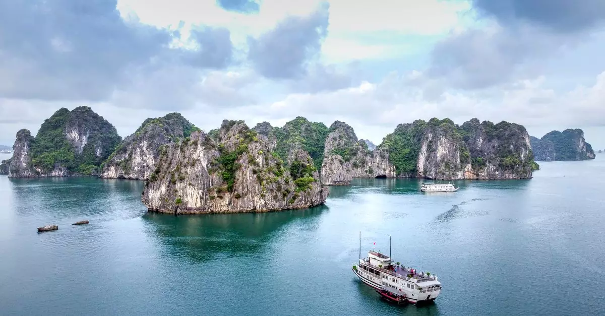 Stunning view of Halong Bay's limestone islands and cruise ship under a cloudy sky.