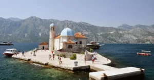 Our Lady of the Rocks island church with tourists in Montenegro's stunning coastal scenery.