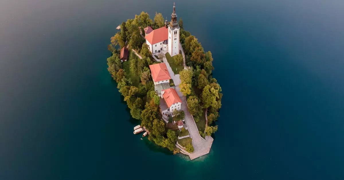 Drone shot capturing the scenic beauty and architecture of Lake Bled island and church.