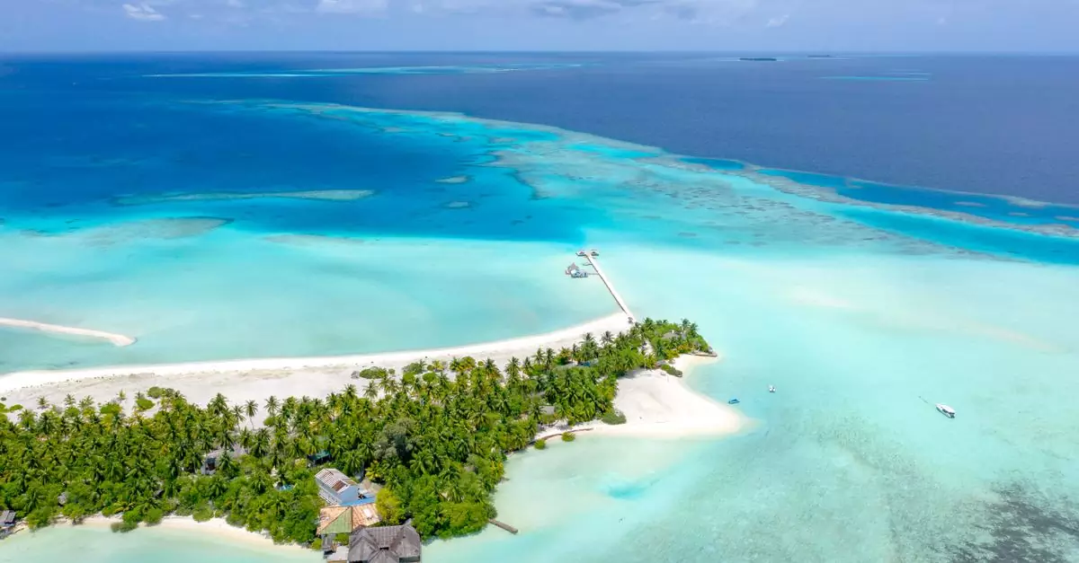 Aerial view of a tropical island with turquoise waters and white sand beaches in the Maldives.