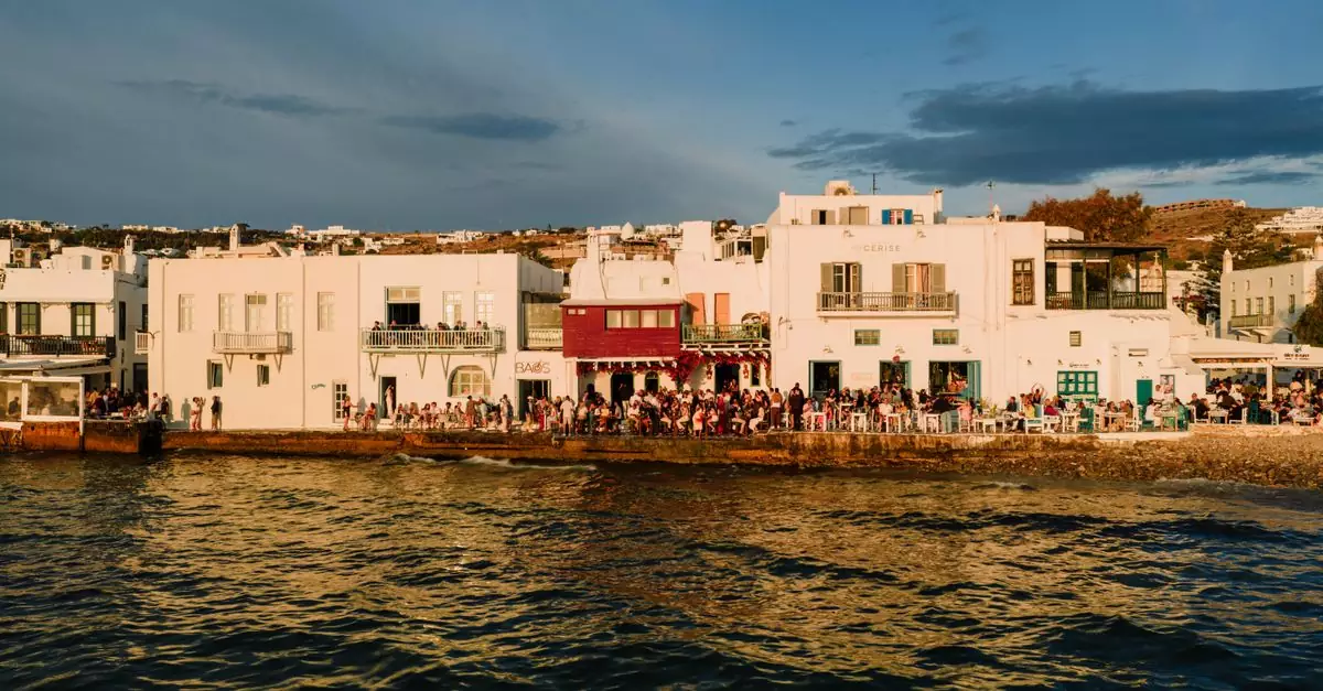 Charming Mykonos waterfront during sunset, showcasing vibrant architecture and lively atmosphere.