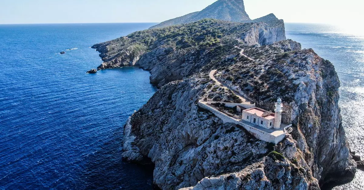 Stunning aerial photo of Punta Grossa Lighthouse on a rocky cliff surrounded by the deep blue ocean.