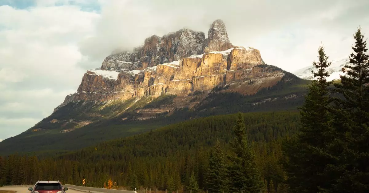 Car on scenic road with view of Castle Mountain in Banff National Park, Canada.