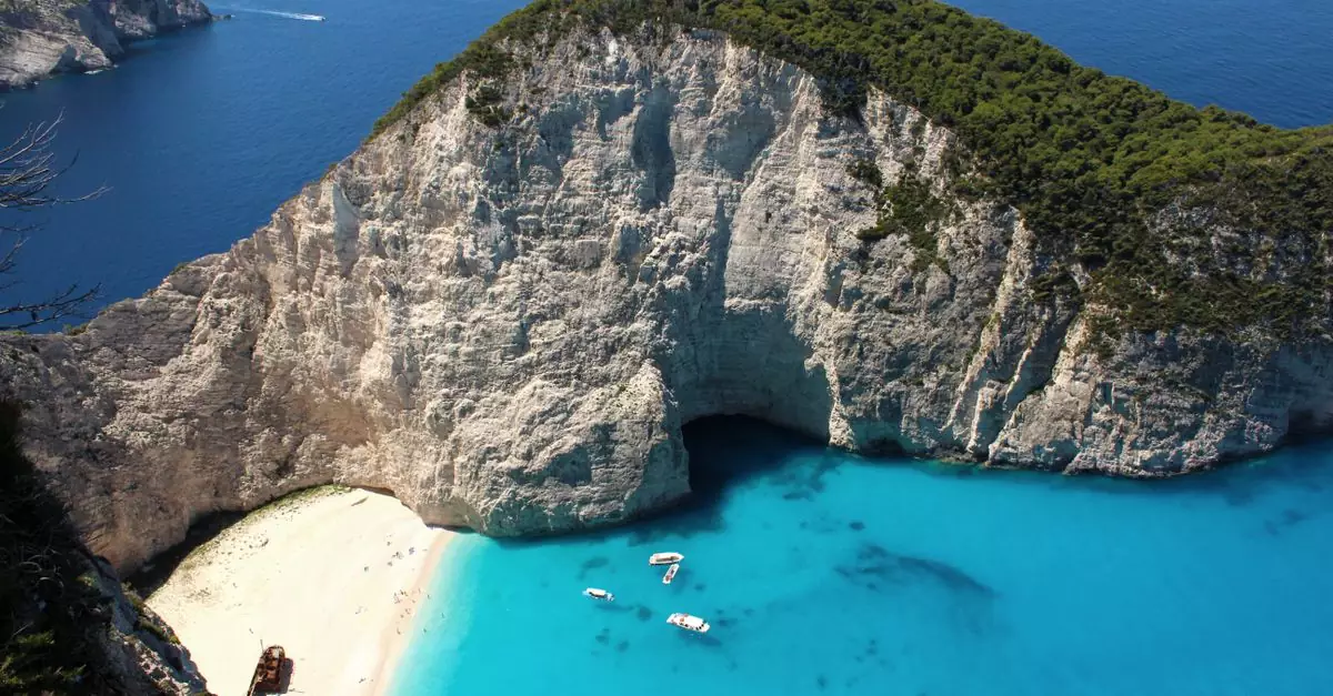 Breathtaking aerial view of Navagio Beach with a towering cliff and clear blue water in Zakynthos, Greece.