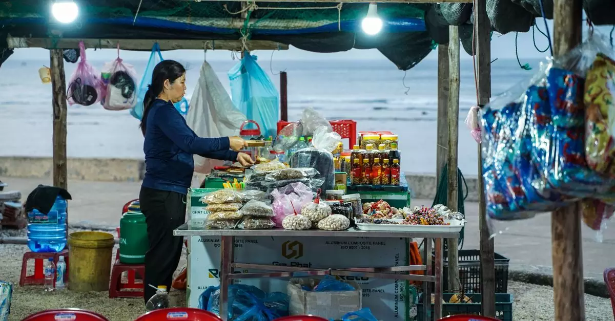 A local vendor woman sells goods at an outdoor coastal market stall in Ly Son.