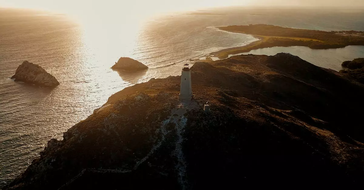Scenic aerial view of a lighthouse on a rocky cliff with a stunning Caribbean sunset in the background.