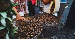 Street vendor roasting chestnuts over open fire in Rome, Italy market.