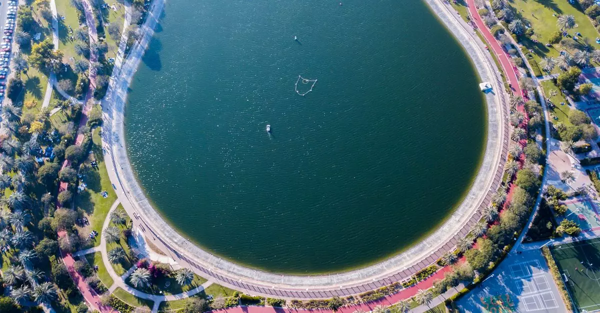 Stunning aerial shot of a circular lake within a lush Dubai park with pathways and greenery.