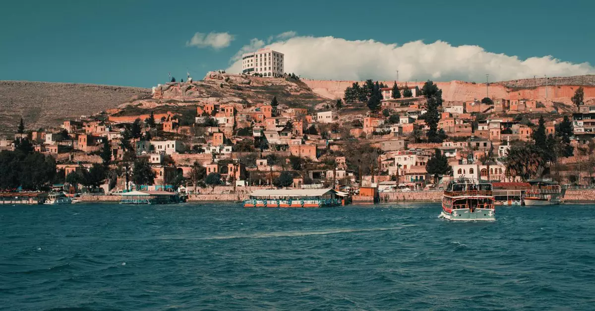 A picturesque village in Halfeti, Turkey by the turquoise waters under a vibrant sky.