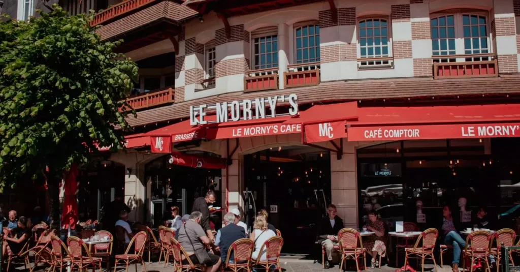 Charming street view of Le Morny's Café in Deauville with people enjoying outdoor seating.