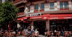 Charming street view of Le Morny's Café in Deauville with people enjoying outdoor seating.