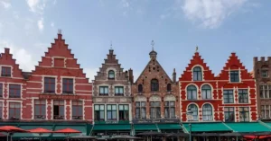 Charming gabled townhouses in Bruges Market Square, showcasing vibrant architecture and bustling atmosphere.