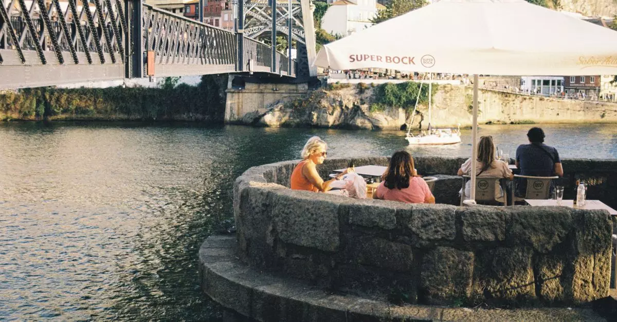 A group of people enjoy a sunny day by Luís I Bridge in Porto, Portugal.