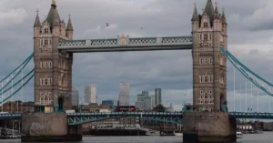 Iconic Tower Bridge view with Thames River in London, capturing classic architecture against a moody skyline.