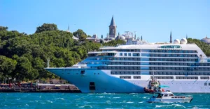 A majestic cruise ship sails through the Bosphorus Strait with a historic Istanbul skyline in the backdrop.