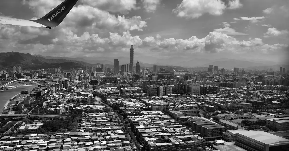 Black and white aerial photo of Taipei City featuring Taipei 101 and an airplane wing.