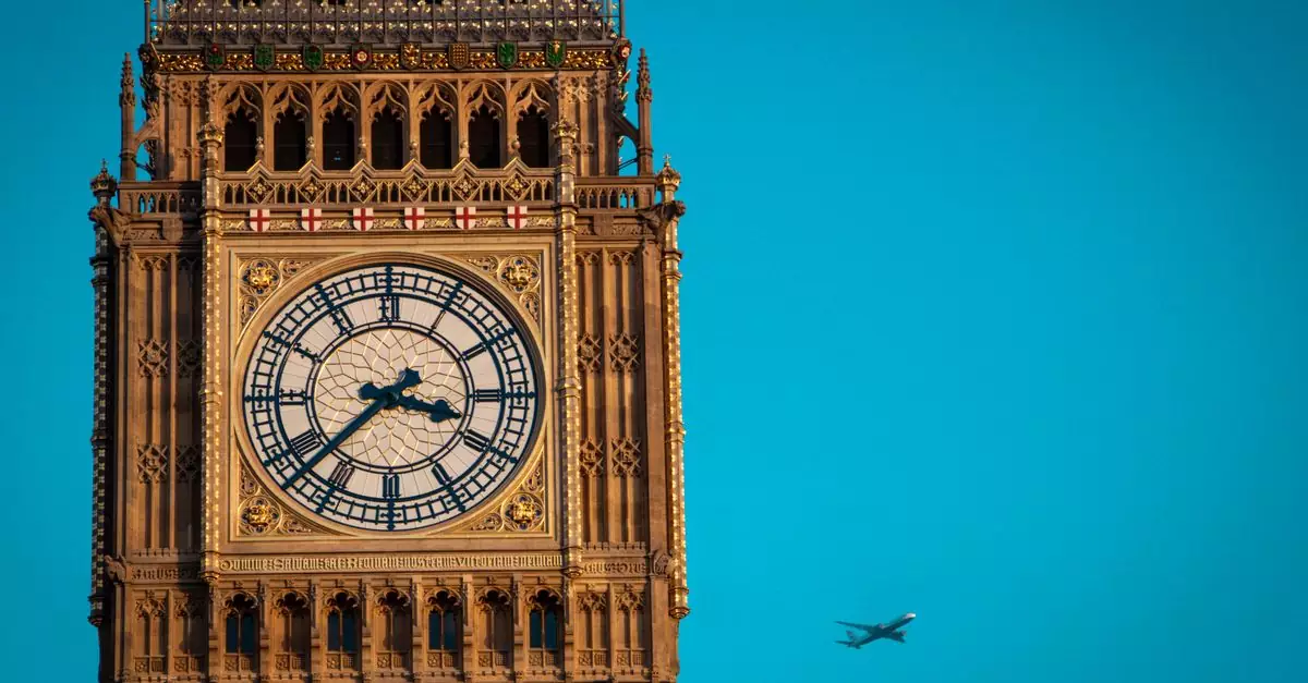 Iconic Big Ben clock tower in London with airplane flying by on a clear day.