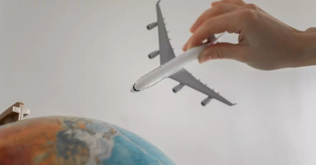A hand holds a toy airplane above a globe, symbolizing travel and exploration.