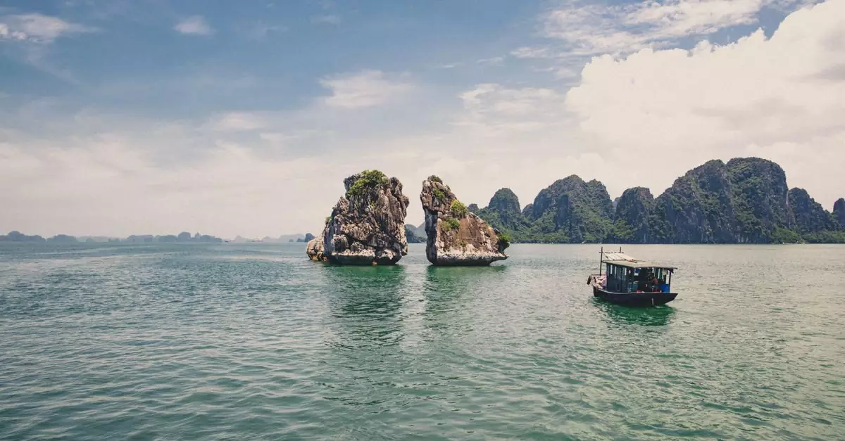 Halong Bay's iconic limestone formations and a traditional boat under a clear sky.