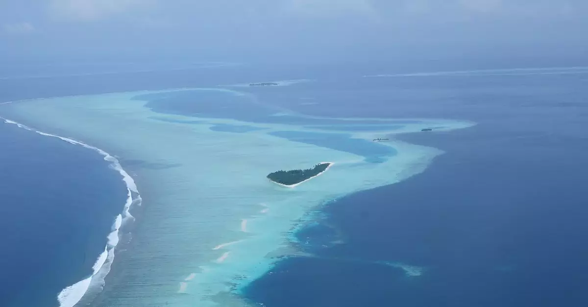 A breathtaking aerial shot of a serene tropical island surrounded by azure waters and coral reefs.