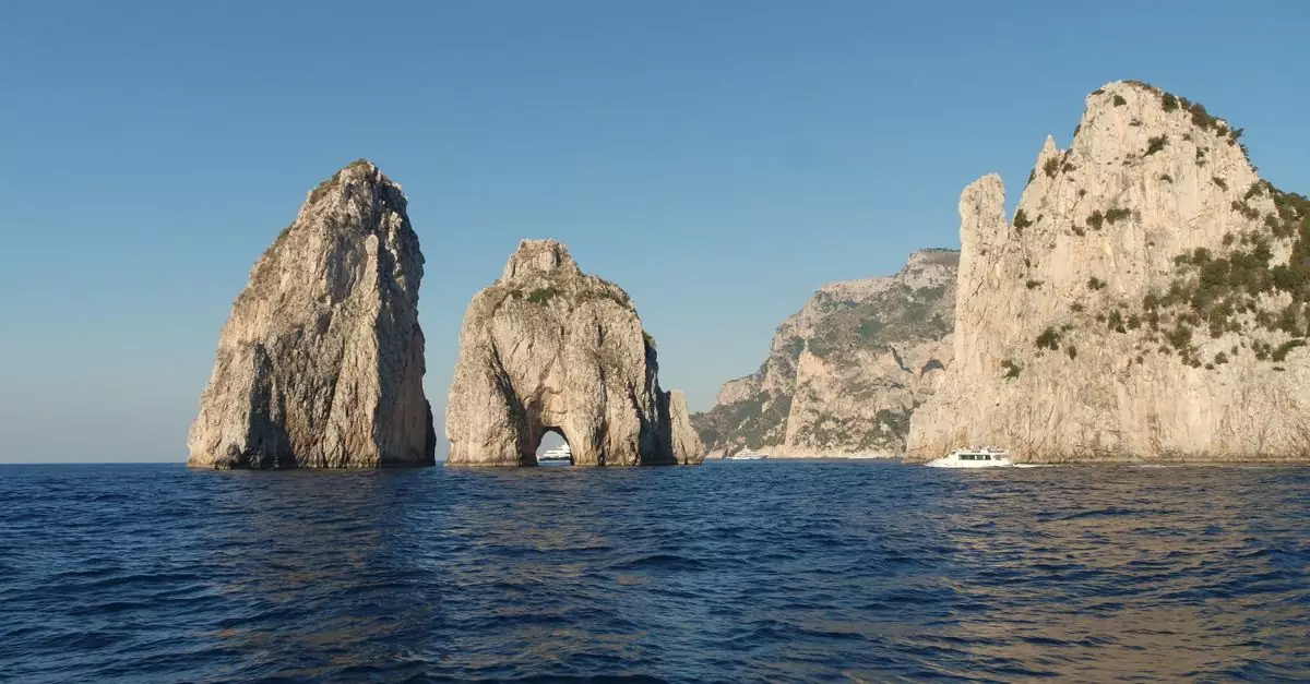Stunning view of the Faraglioni rock formations off the coast of Capri, Italy, under a clear blue sky.