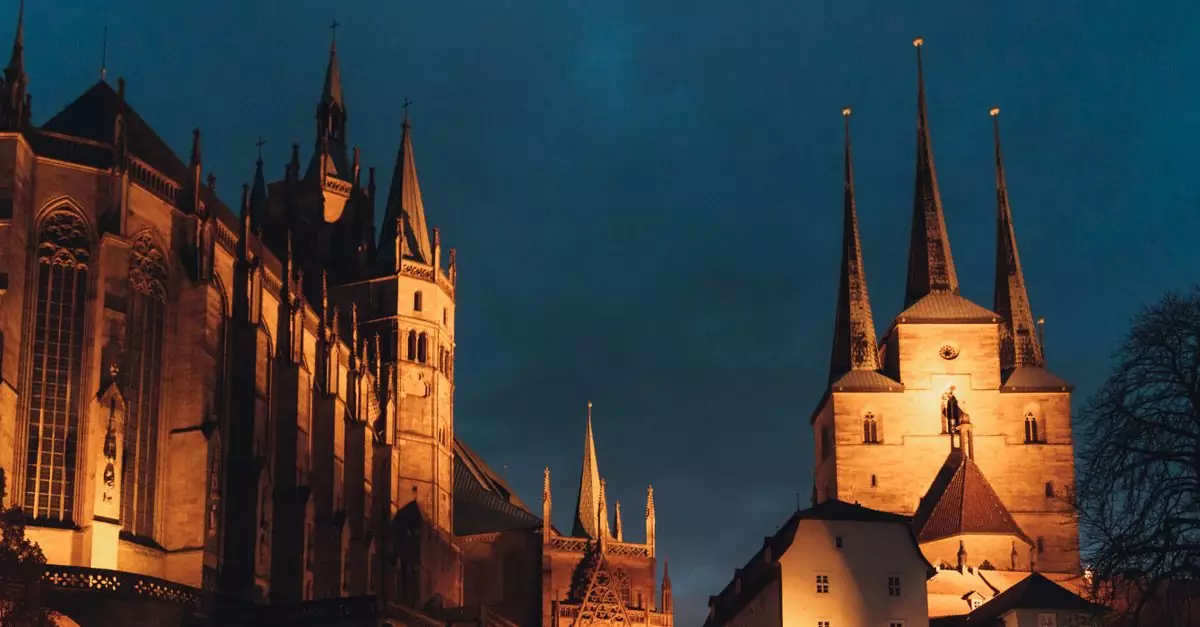 A stunning view of Erfurt Cathedral and St Severus Church illuminated at night, showcasing gothic architecture.