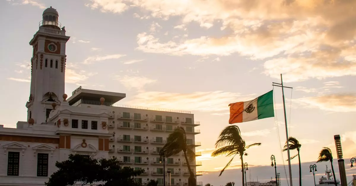 Beautiful Mexican flag waving near a historic clock tower at sunset in Veracruz.