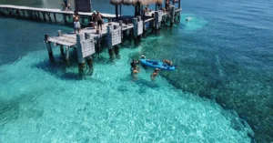 People enjoying a sunny day at Isla Mujeres pier with clear water and vibrant scenery.