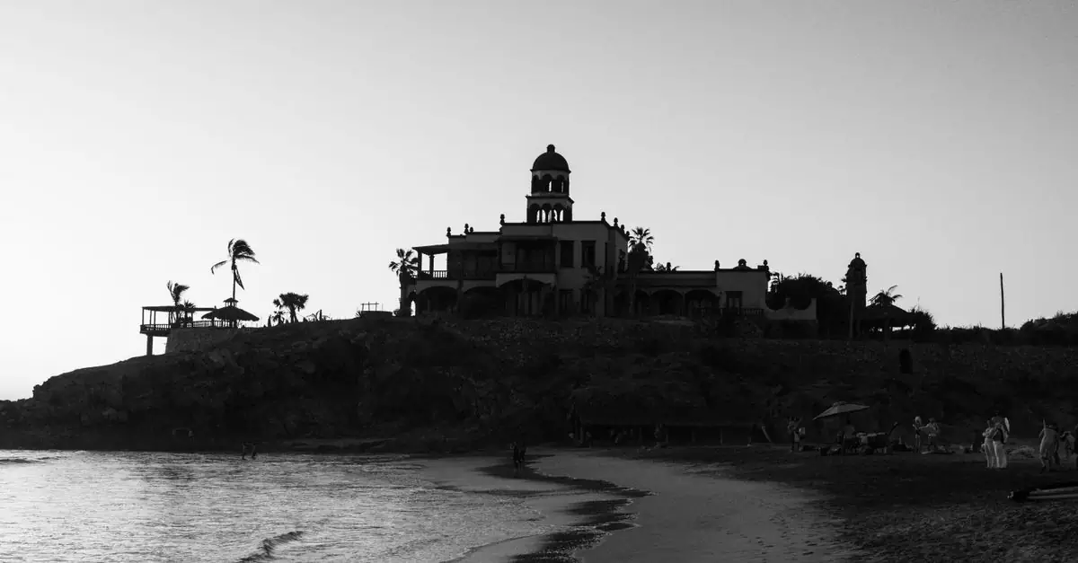Silhouette of an architectural building on a beach during sunset in black and white.