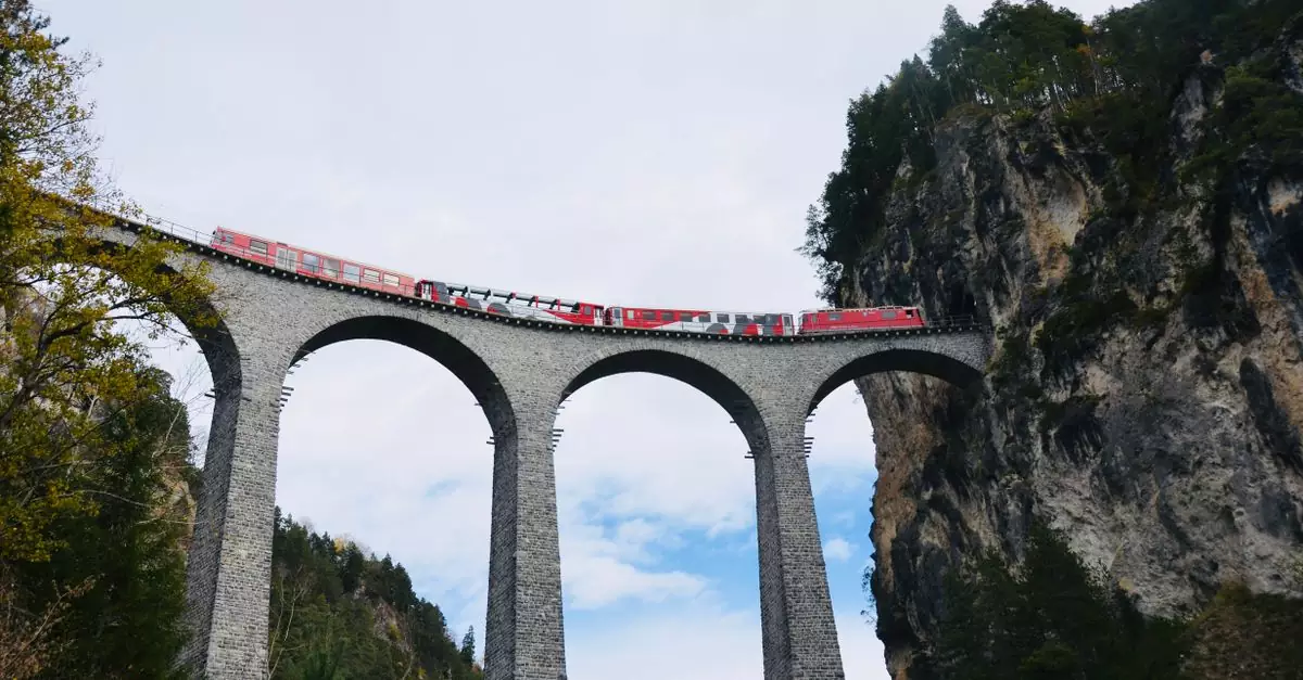 Stunning view of red train crossing the iconic Landwasser Viaduct in the Swiss Alps.