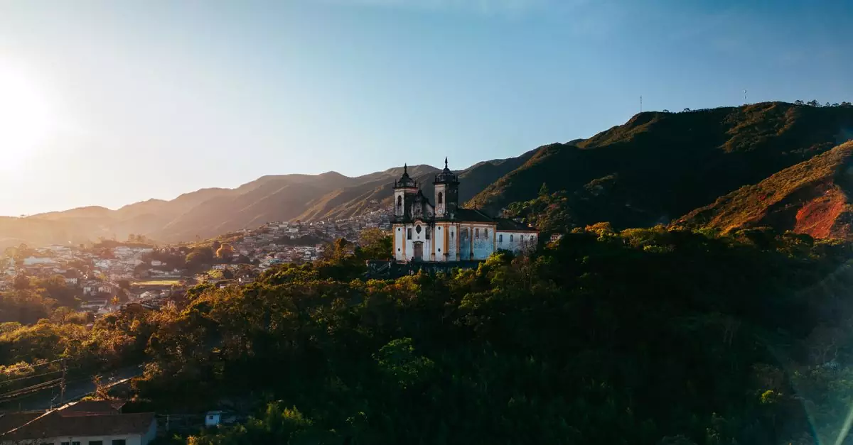 A stunning view of a historic church in Ouro Preto, Brazil, against a mountainous backdrop at sunset.