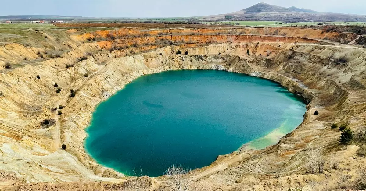 Aerial shot of a stunning turquoise crater lake surrounded by rocky formations.