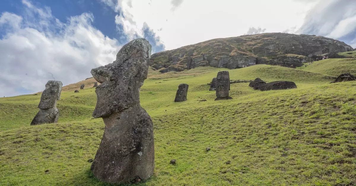 Capture of iconic Moai statues on a grassy hillside in Easter Island, Chile under a bright sky.