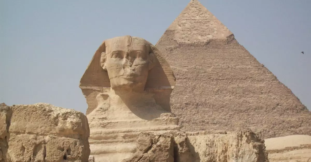 View of the Great Sphinx and Pyramid in Giza, Egypt, under a clear sky.