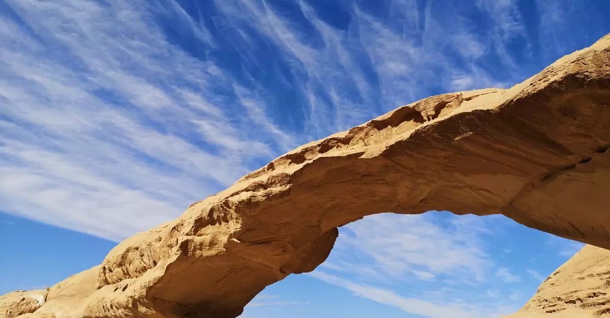 Stunning natural rock arch in Jordan under a clear blue sky, perfect for nature enthusiasts.