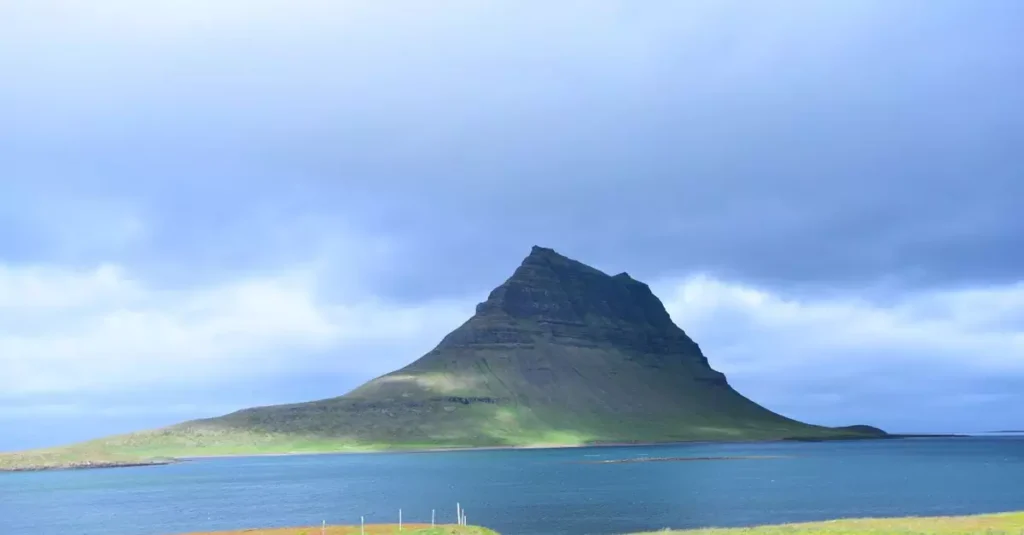 Majestic view of Kirkjufell mountain by the sea under a cloudy sky in Iceland.