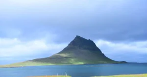 Majestic view of Kirkjufell mountain by the sea under a cloudy sky in Iceland.